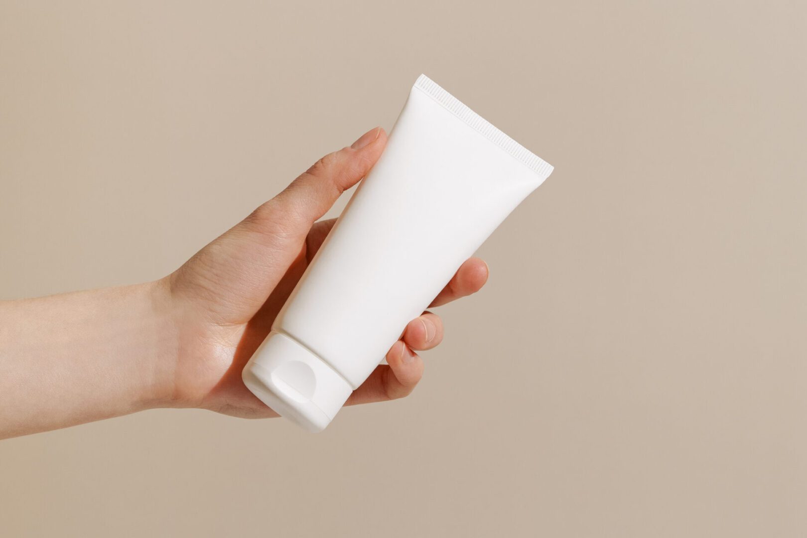Person holding plain cosmetic tube